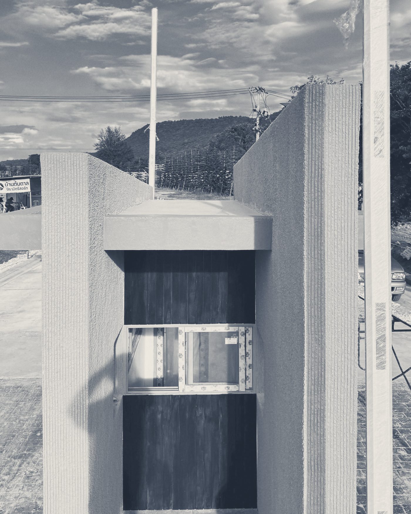 The Main Gate guardhouse up close: a dark timber panel and window between two walls of textured render