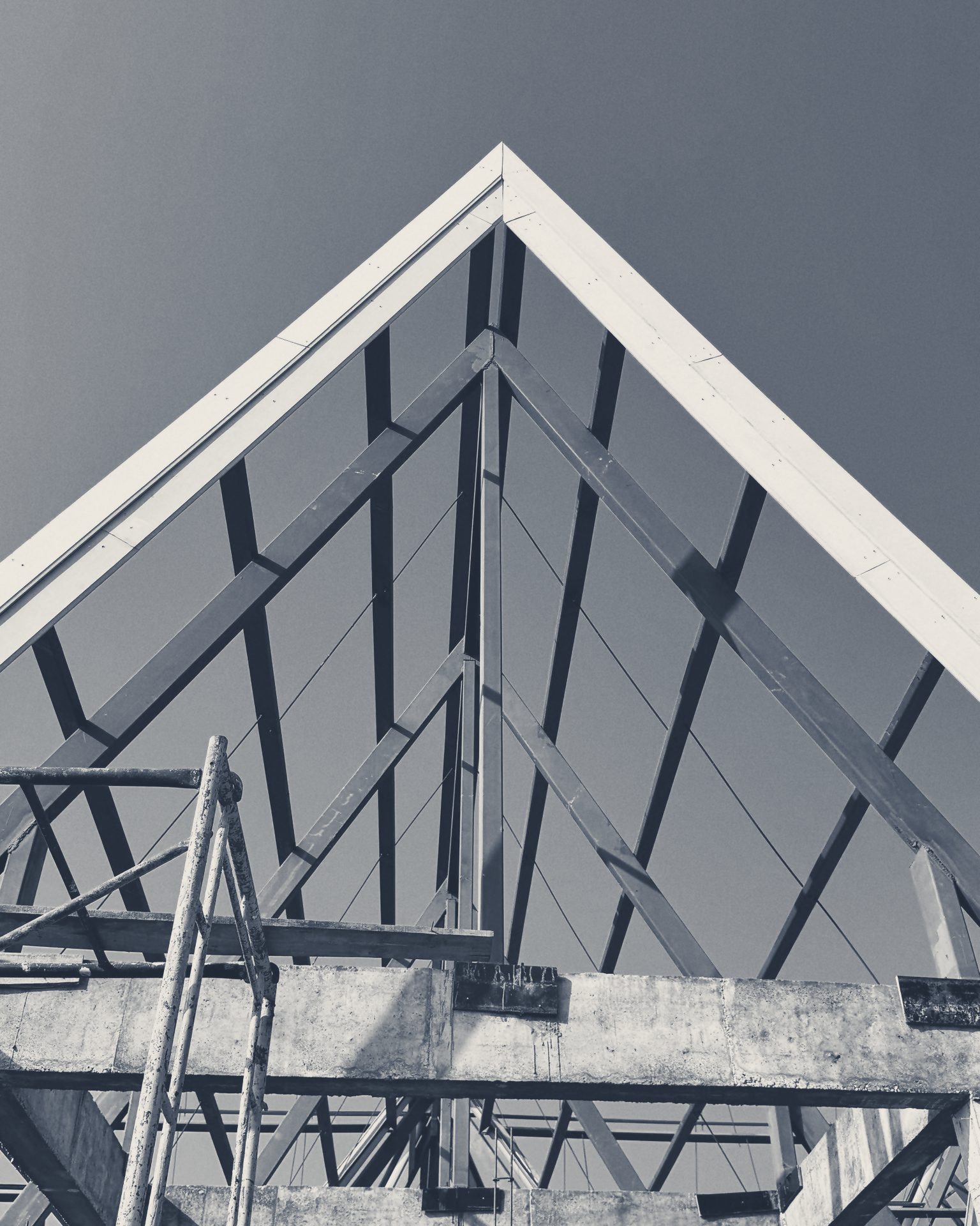 Steel roof trusses inside a Club House gable, seen from below against the sky
