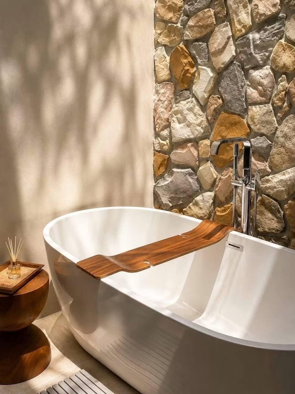 A freestanding bath against a stone wall in the finished Khao Yai villa