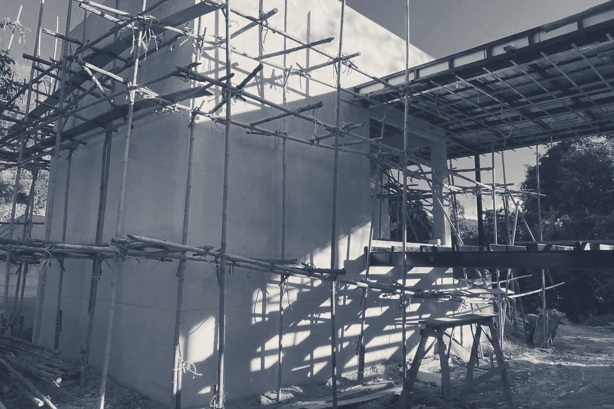 Late sun throws the bamboo scaffold’s shadows across the rendered walls of the Khao Yai villa, before the timber cladding went on