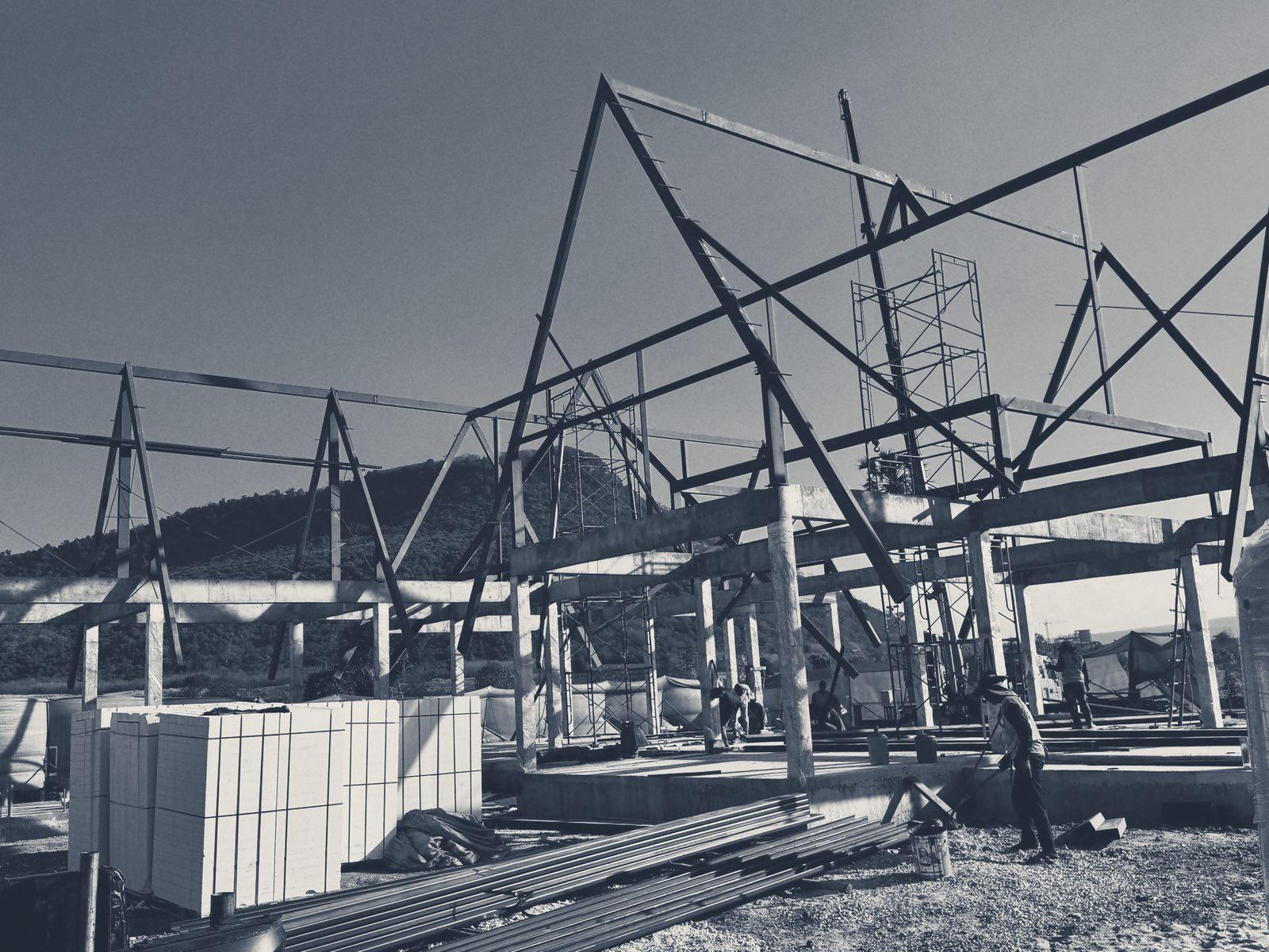 Steel roof frames of the Club House going up at Baan Ton Tan, with a hill behind