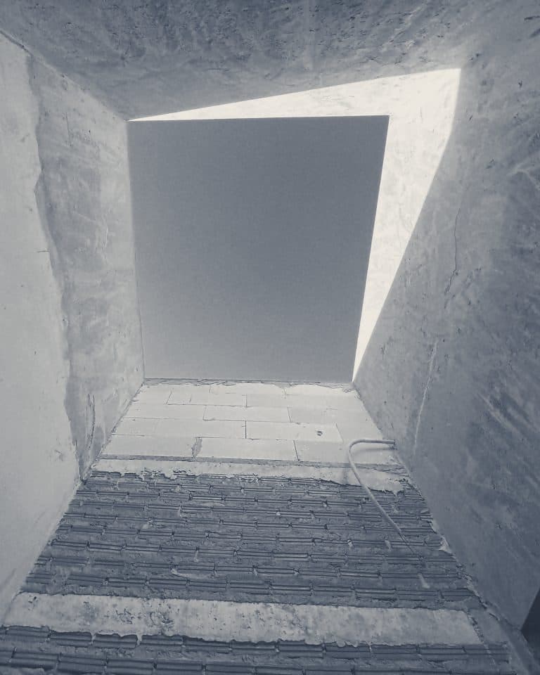 Looking up a concrete and brick skylight shaft to the sky.