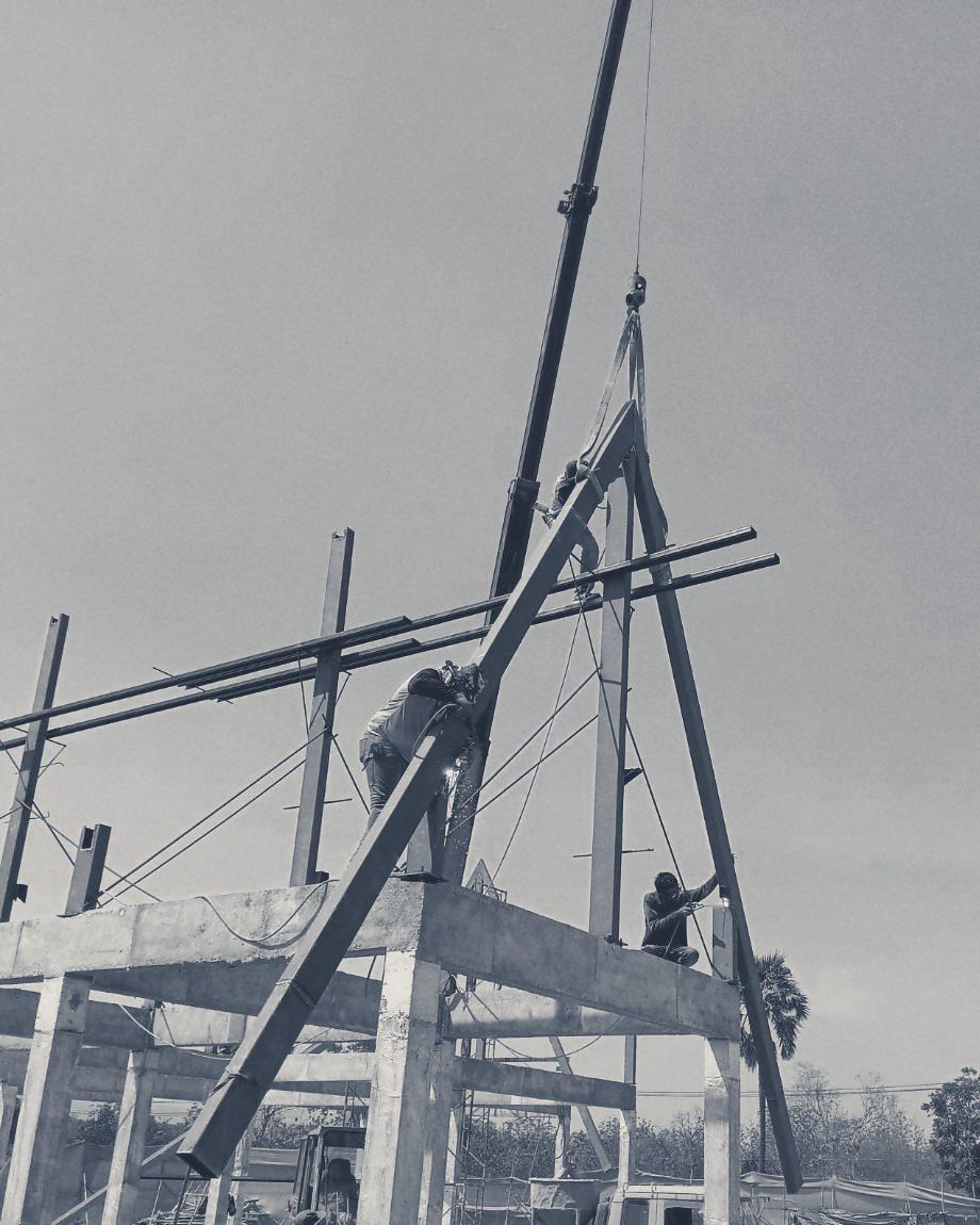 A crane lifting a steel rafter onto the Club House frame