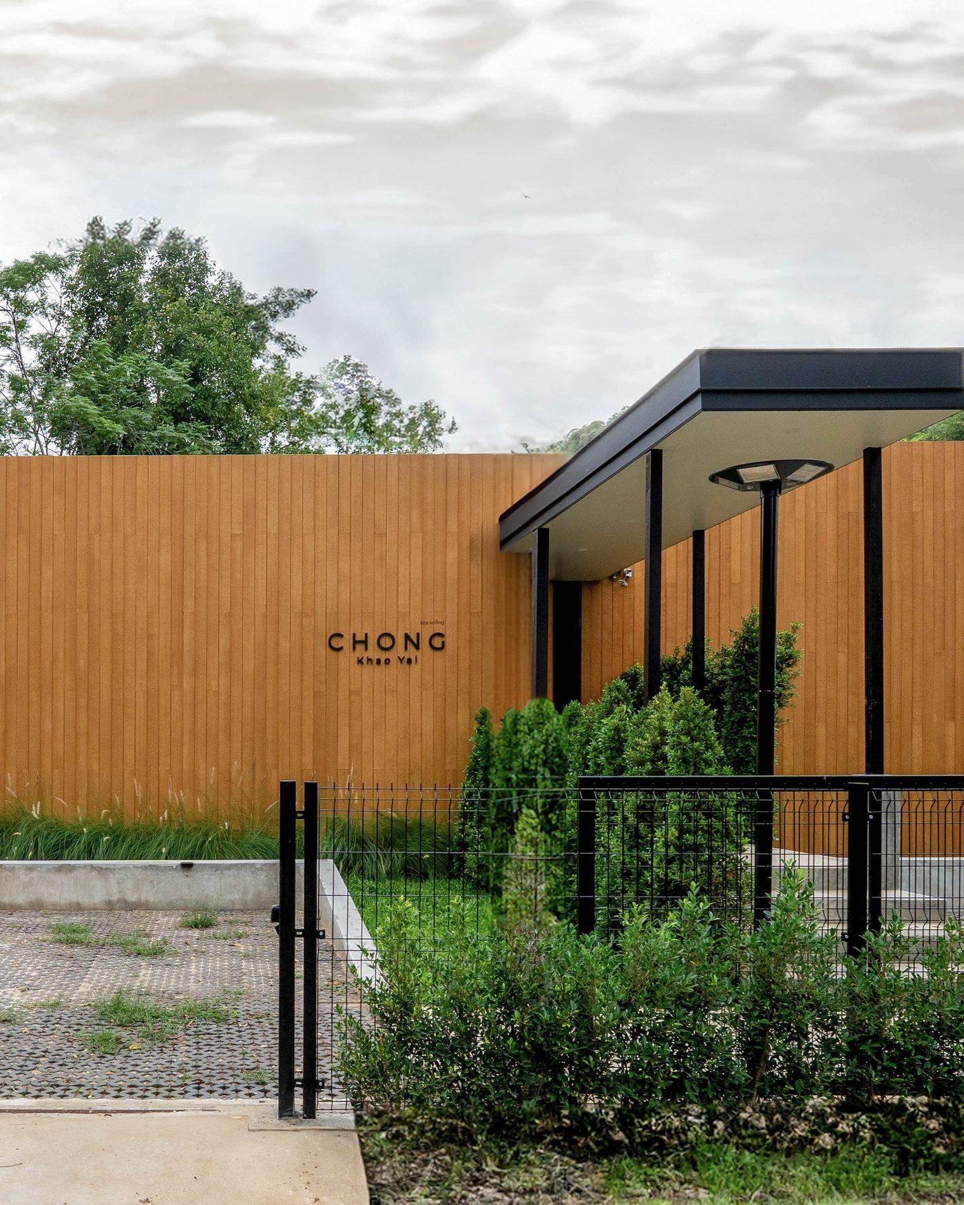 The finished Khao Yai villa from the road: the open gate, the entrance canopy and the timber wall with the house name