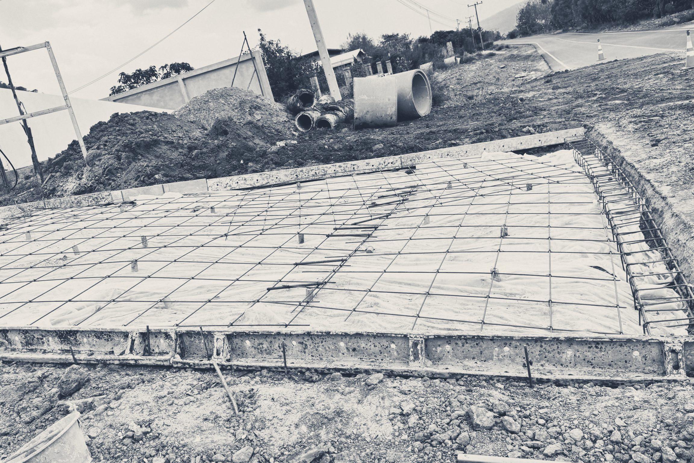 Slab mesh laid over plastic sheeting, with heaps of soil behind
