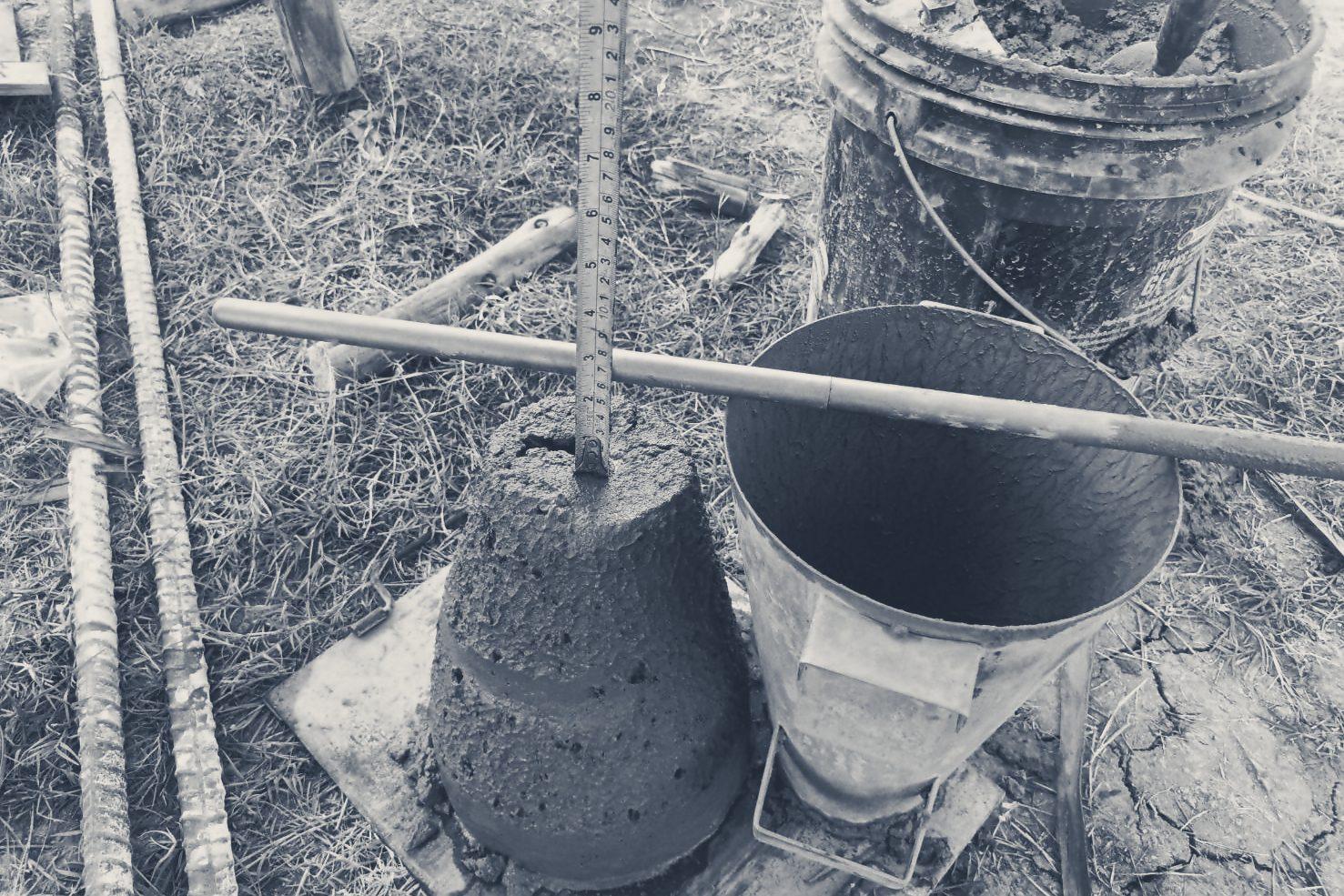 A concrete slump test: the slumped cone, the empty mould and a tape measure