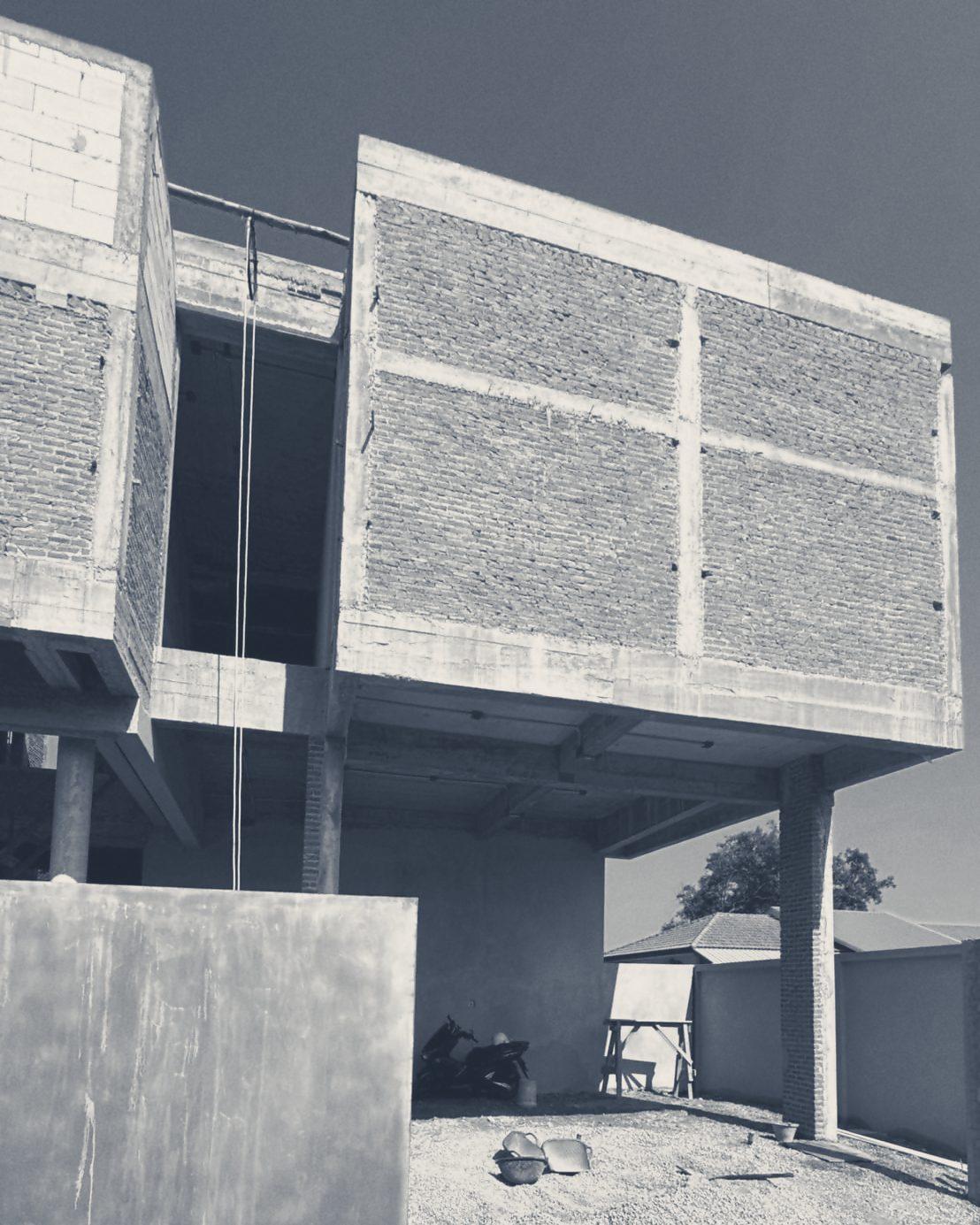 JP House from the side yard: two brick-clad volumes on a concrete frame against a clear sky