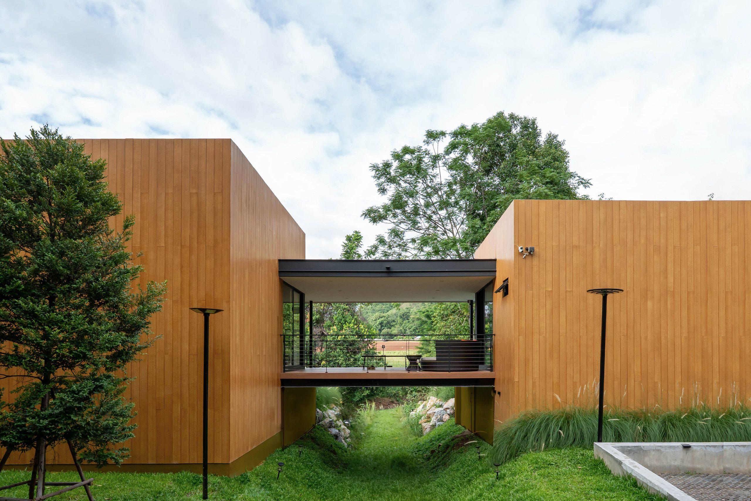 The two timber-clad wings of the villa joined by a covered bridge