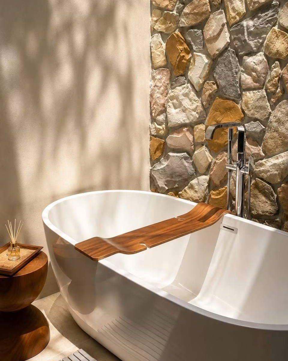 The finished bathroom: a freestanding bath against a stone wall
