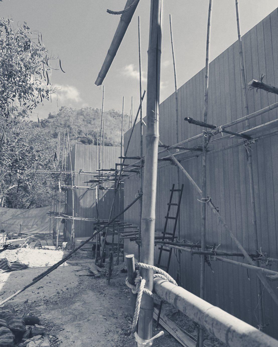 Timber cladding going on behind bamboo scaffold along the walkway