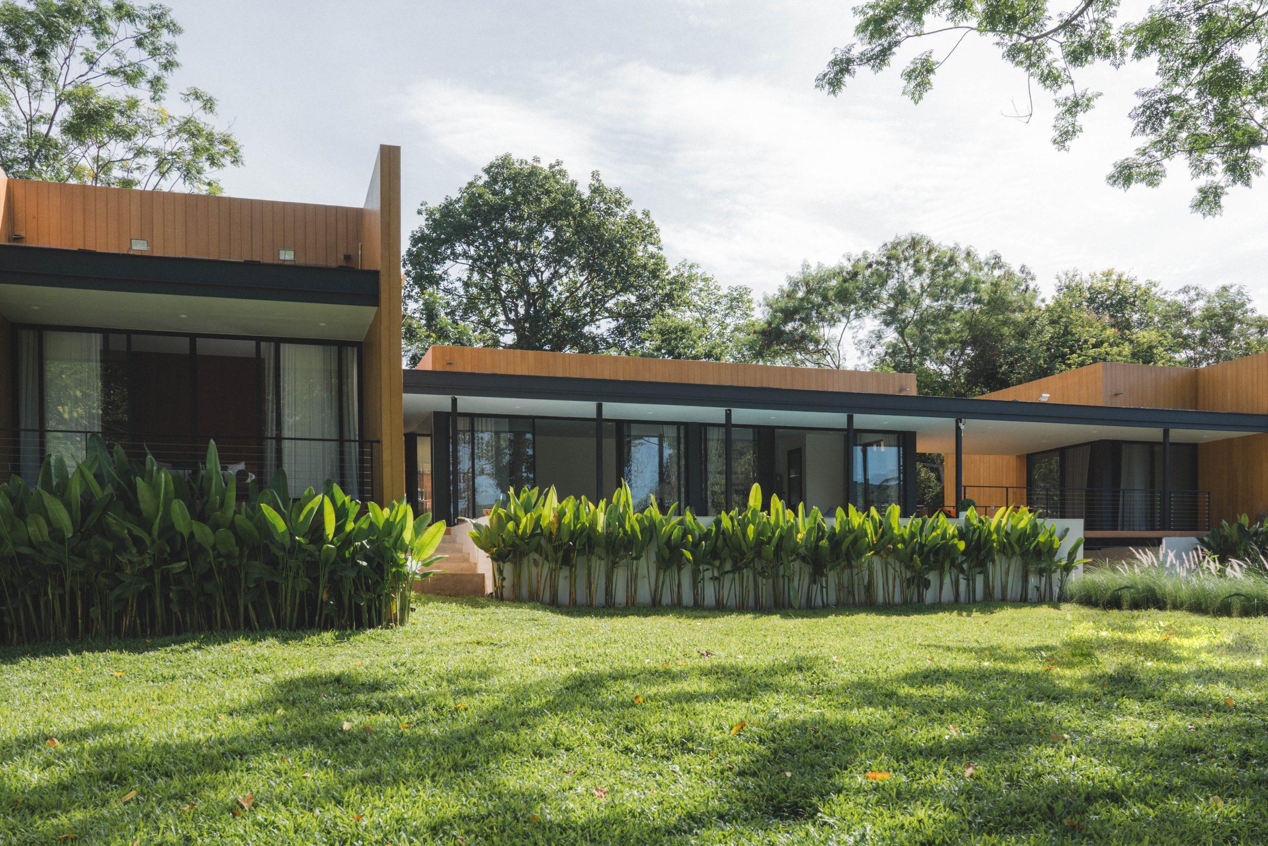 The villa in its garden, timber-clad volumes behind a lawn