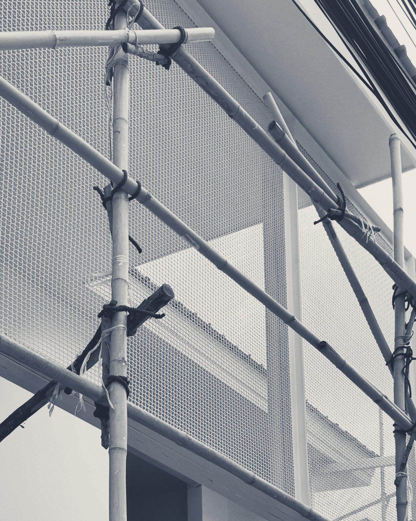 Perforated metal screens going up behind the bamboo scaffold