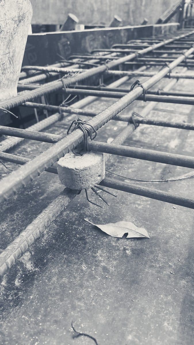 Slab rebar on concrete spacers, with a fallen leaf on the formwork