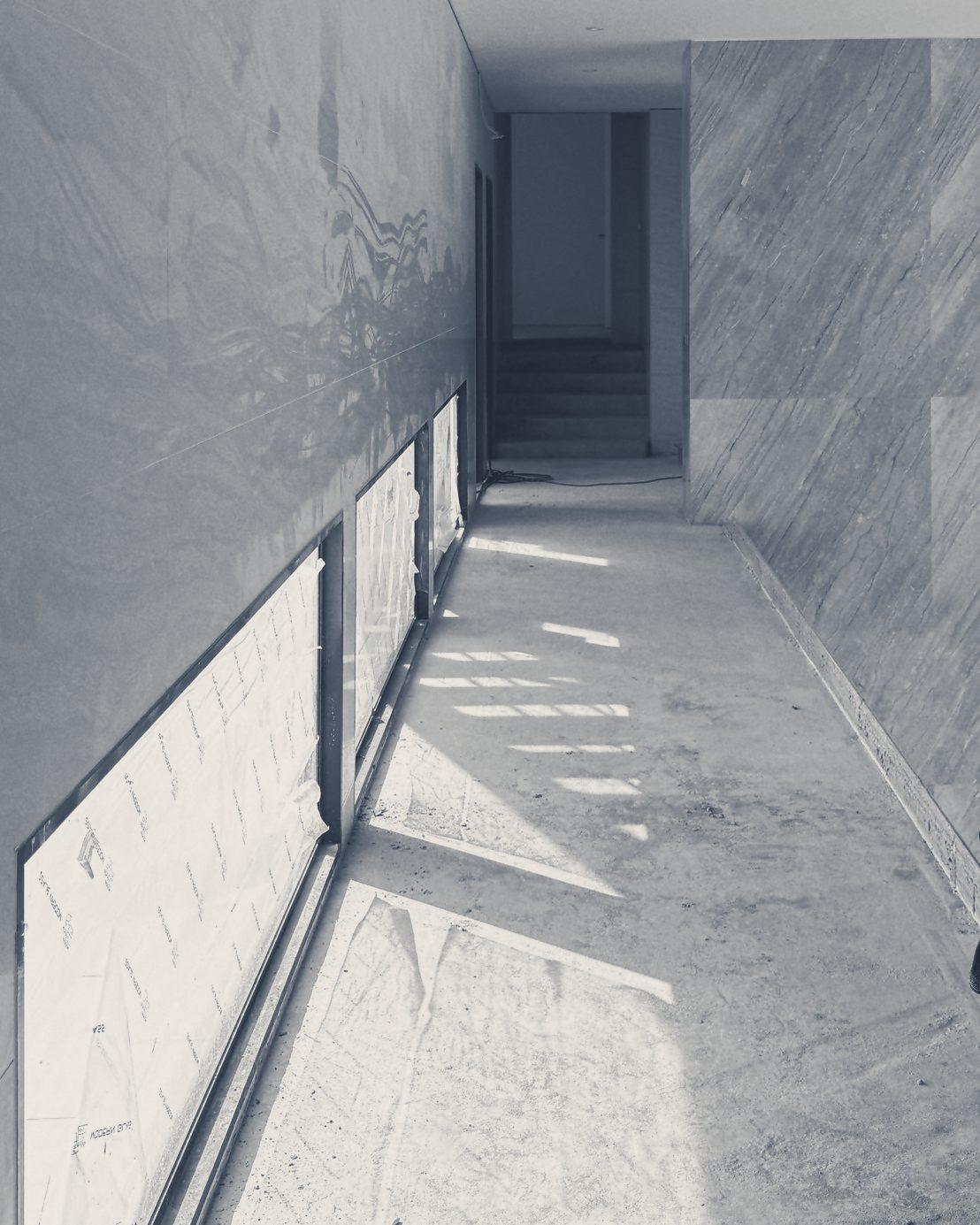 A corridor lined with stone-look panels and slim windows