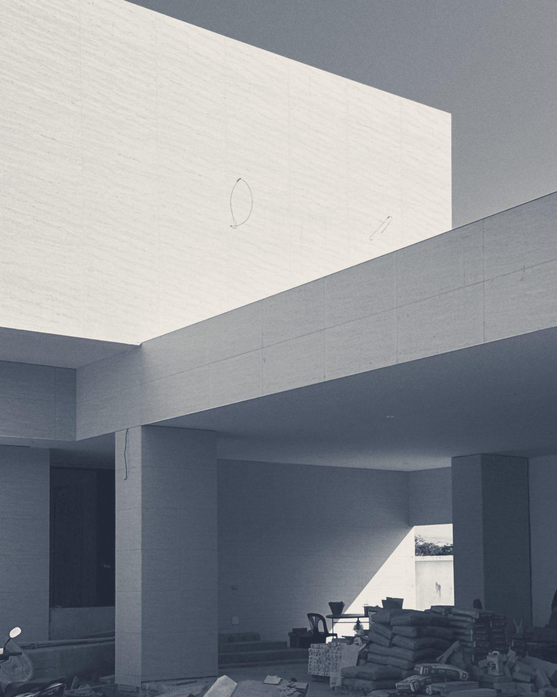 The carport under the cantilevered upper floor, with building materials stacked below