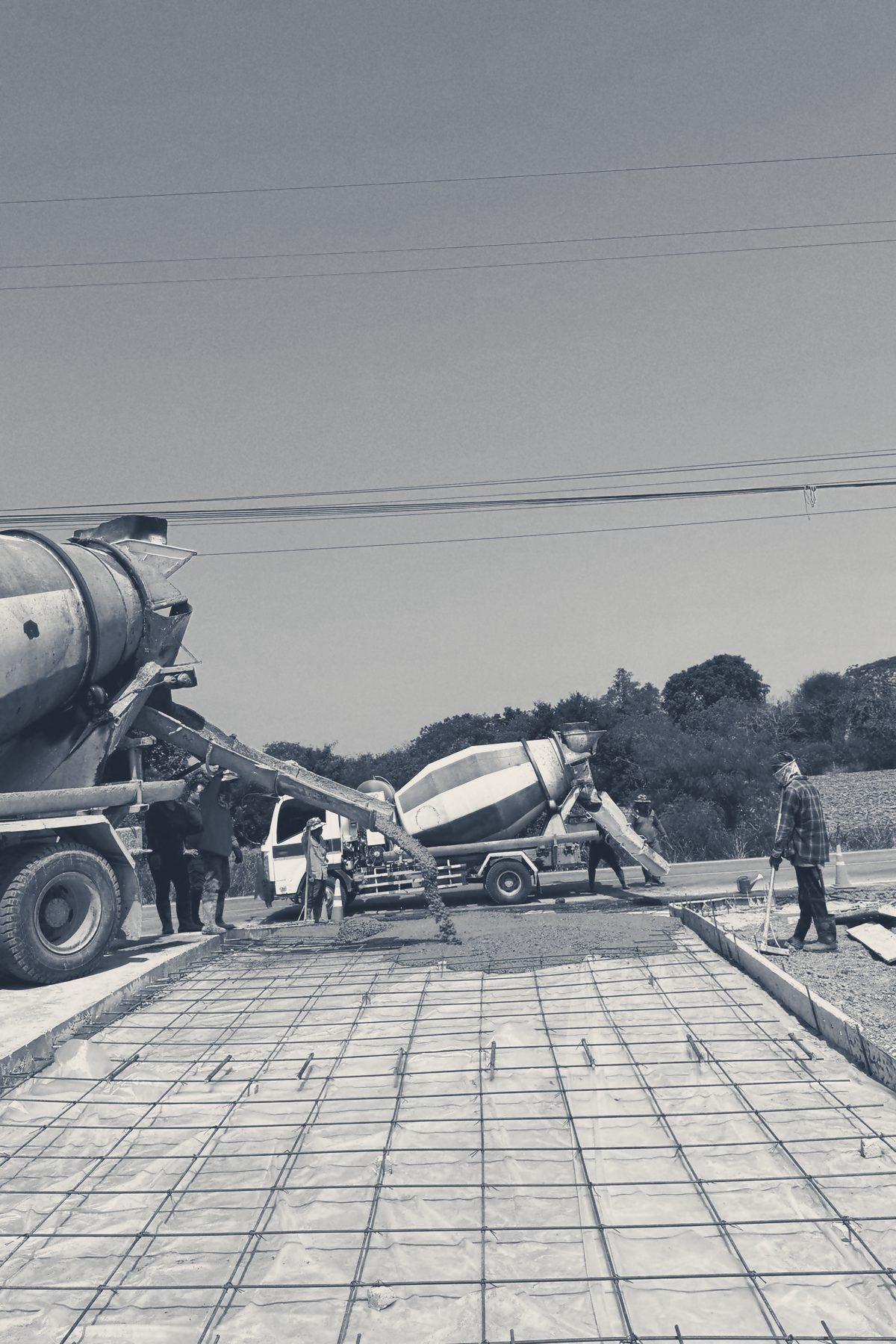 Pour day at Main Gate: concrete runs down a mixer truck’s chute onto the slab mesh