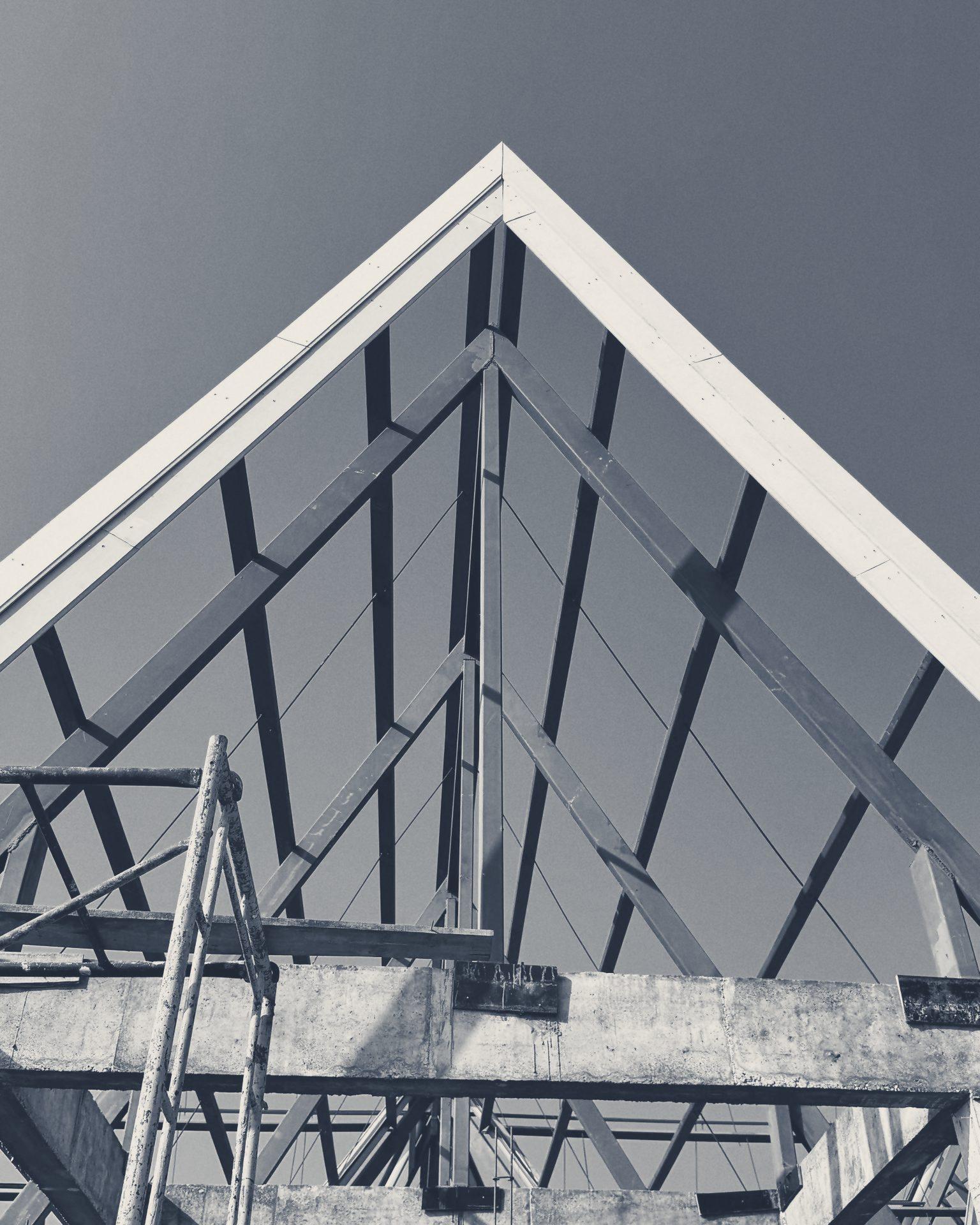 Steel roof trusses inside a Club House gable, seen from below against the sky