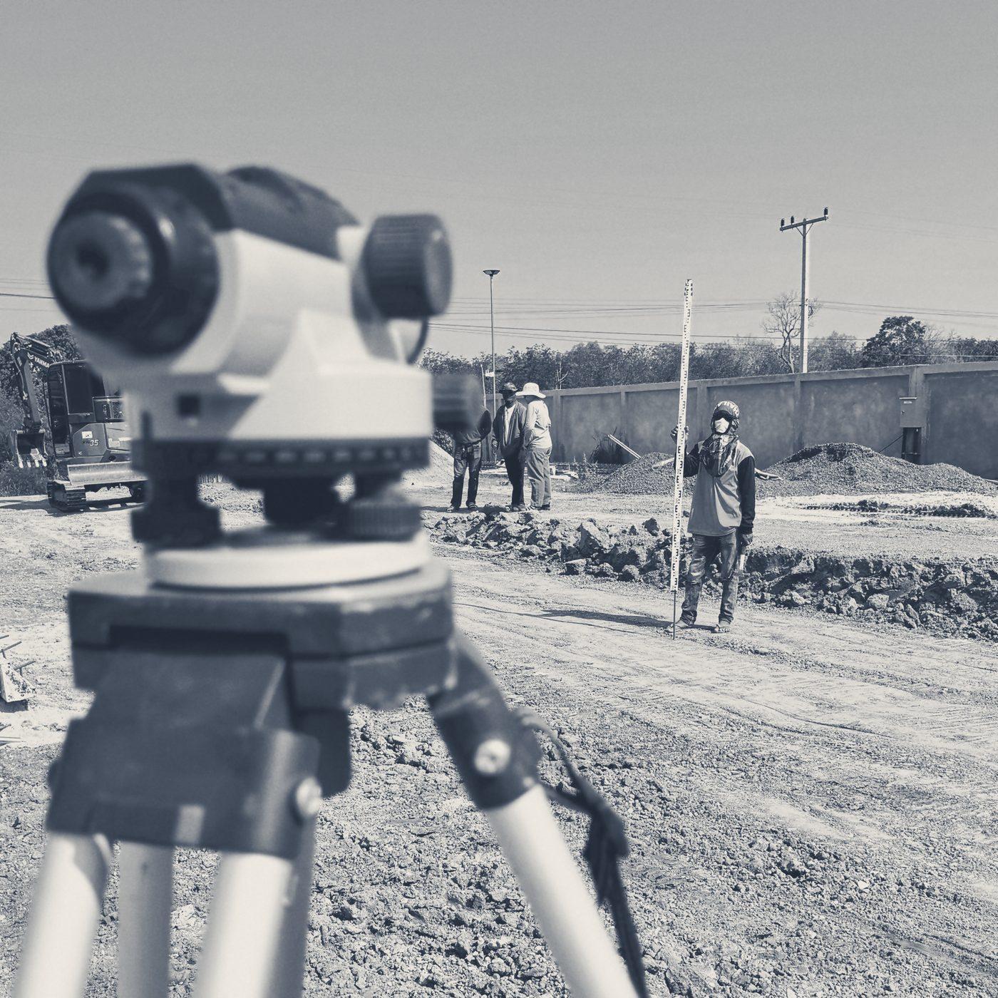 A survey level on its tripod over graded ground at the Main Gate site
